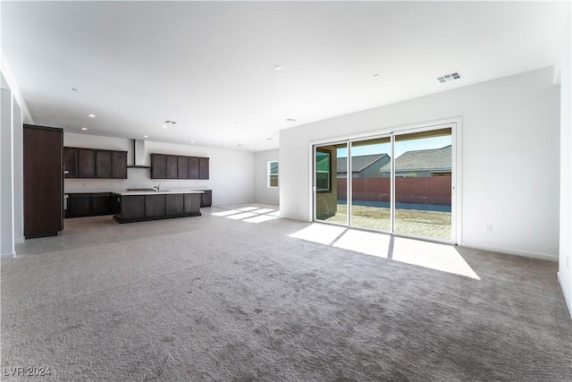 unfurnished living room featuring light colored carpet and sink