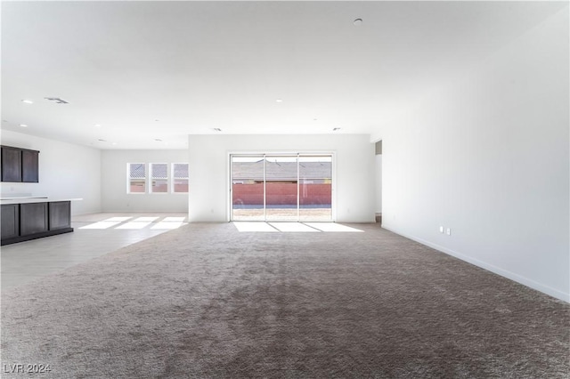 unfurnished living room with light carpet and a healthy amount of sunlight