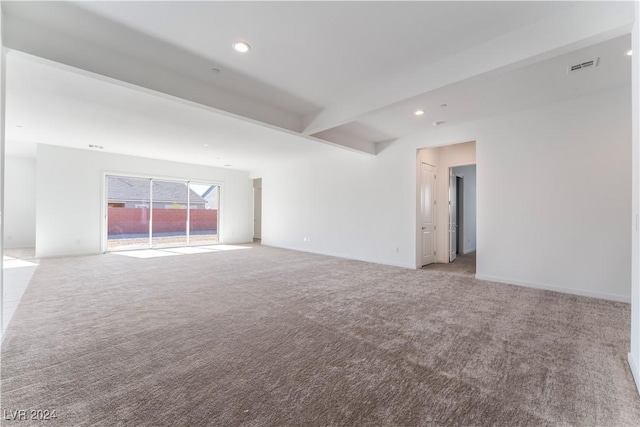 empty room with beam ceiling and light colored carpet