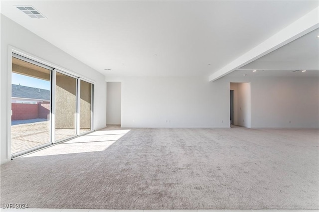 spare room with beam ceiling and light carpet