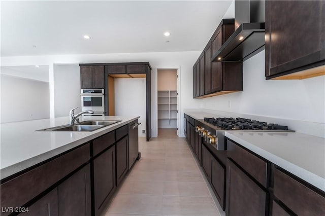 kitchen with sink, wall chimney exhaust hood, dark brown cabinets, light tile patterned flooring, and appliances with stainless steel finishes