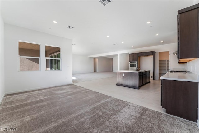 kitchen with dark brown cabinets, stainless steel appliances, a kitchen island, and sink