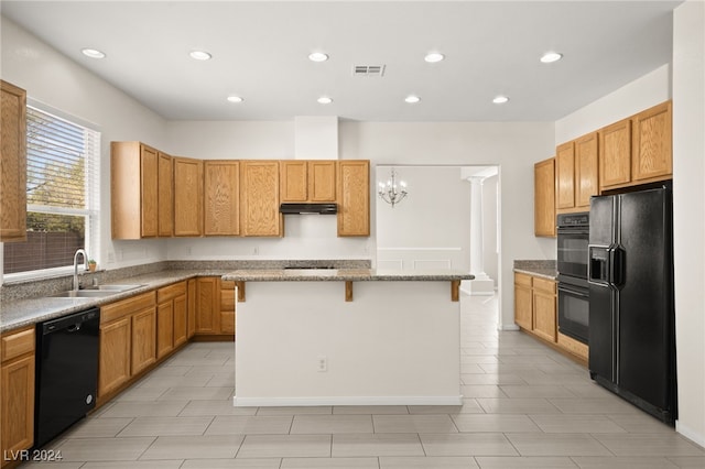 kitchen with a kitchen breakfast bar, sink, black appliances, a notable chandelier, and a center island