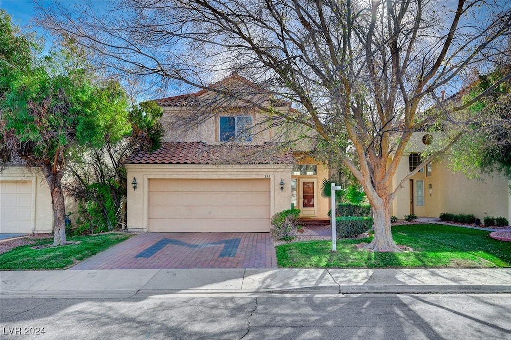 mediterranean / spanish house with a garage and a front lawn