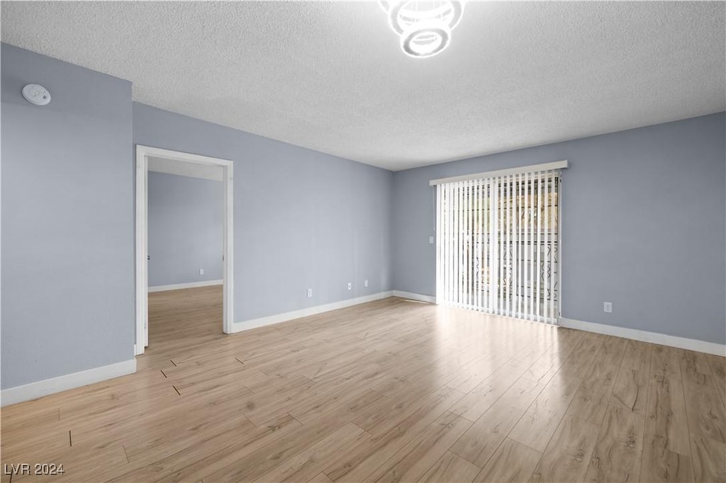 unfurnished room featuring a textured ceiling and light wood-type flooring