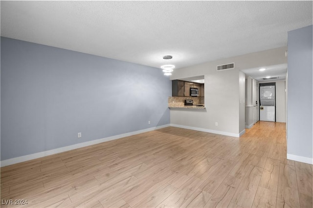 unfurnished living room featuring a textured ceiling and light wood-type flooring