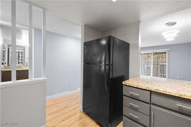 kitchen featuring black refrigerator, light hardwood / wood-style flooring, and a textured ceiling