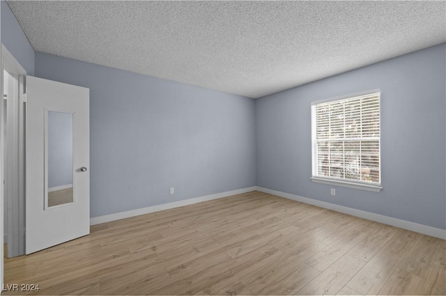 unfurnished room featuring a textured ceiling and light wood-type flooring