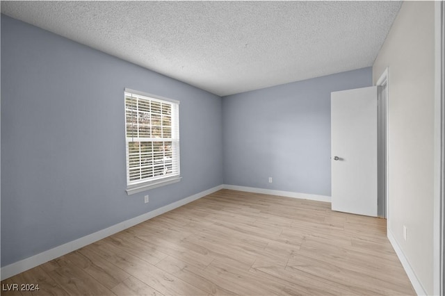 empty room featuring a textured ceiling and light hardwood / wood-style floors