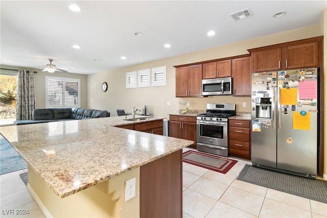 kitchen featuring ceiling fan, sink, light stone counters, light tile patterned floors, and appliances with stainless steel finishes