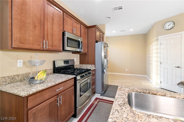 kitchen featuring light stone counters, sink, light tile patterned flooring, and appliances with stainless steel finishes