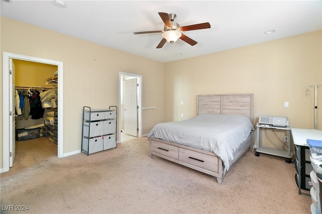 bedroom featuring light carpet, a walk in closet, a closet, and ceiling fan