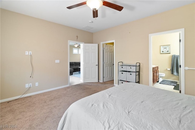 bedroom with ceiling fan, light carpet, and ensuite bath