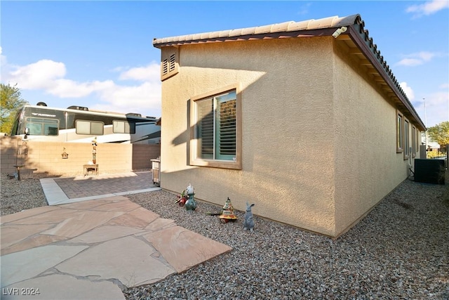 view of side of home with central AC unit and a patio