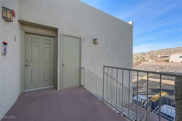 view of exterior entry with a mountain view and a balcony