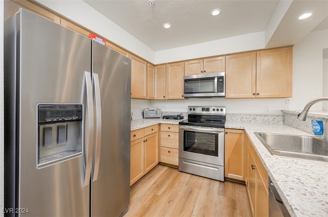 kitchen with light brown cabinets, sink, light hardwood / wood-style floors, and stainless steel appliances