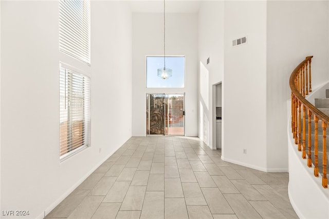 hallway with a high ceiling and an inviting chandelier