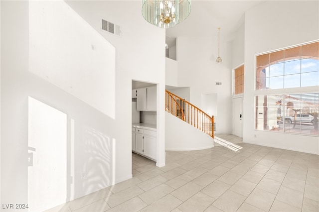 entryway with a towering ceiling, an inviting chandelier, and light tile patterned floors