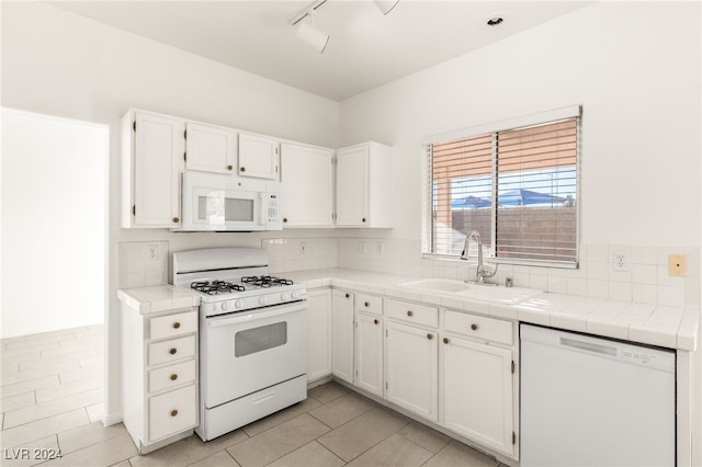 kitchen featuring white appliances, white cabinetry, tile countertops, and sink