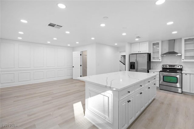 kitchen featuring stainless steel appliances, a kitchen island, white cabinets, and wall chimney exhaust hood