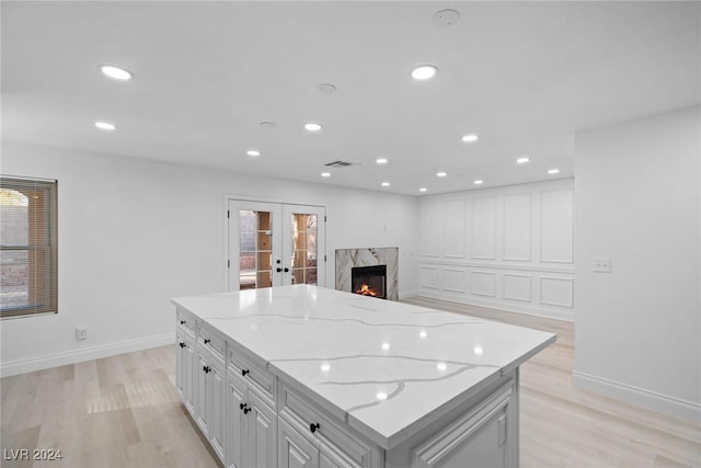 kitchen with white cabinets, a premium fireplace, a center island, and light stone countertops