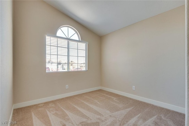 carpeted spare room featuring vaulted ceiling and plenty of natural light