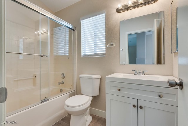 full bathroom with hardwood / wood-style flooring, vanity, shower / bath combination with glass door, and toilet