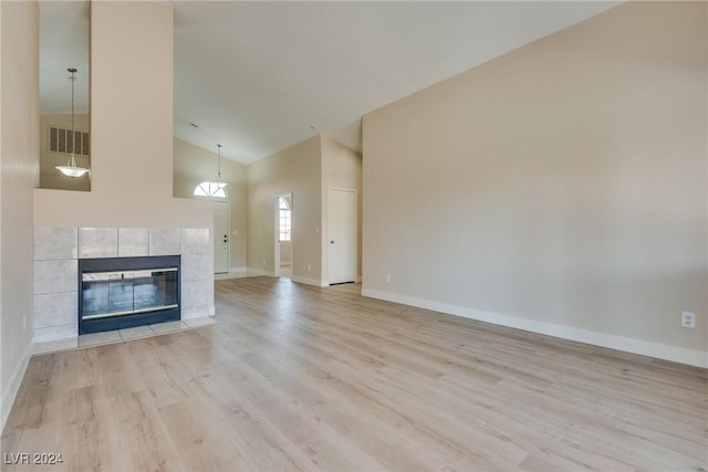 unfurnished living room with a fireplace, high vaulted ceiling, and light hardwood / wood-style flooring