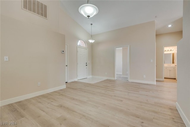 foyer with high vaulted ceiling and light wood-type flooring