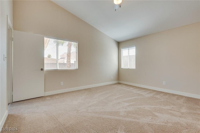 spare room with ceiling fan, light colored carpet, and vaulted ceiling