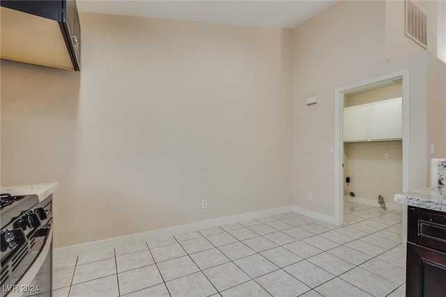 kitchen featuring dark brown cabinets, light tile patterned floors, and range with gas cooktop