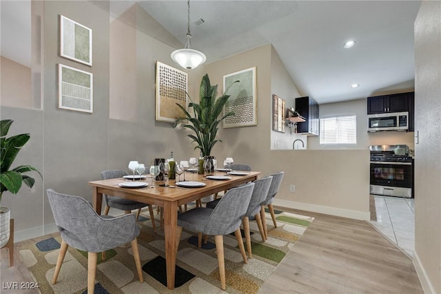 dining room featuring vaulted ceiling and light wood-type flooring