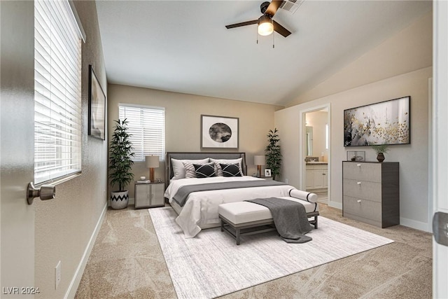 bedroom featuring vaulted ceiling, light carpet, ceiling fan, and ensuite bath