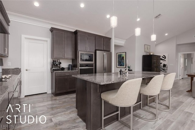 kitchen featuring light stone countertops, pendant lighting, vaulted ceiling, a center island with sink, and appliances with stainless steel finishes