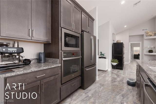 kitchen featuring dark brown cabinetry, light stone countertops, lofted ceiling, and appliances with stainless steel finishes