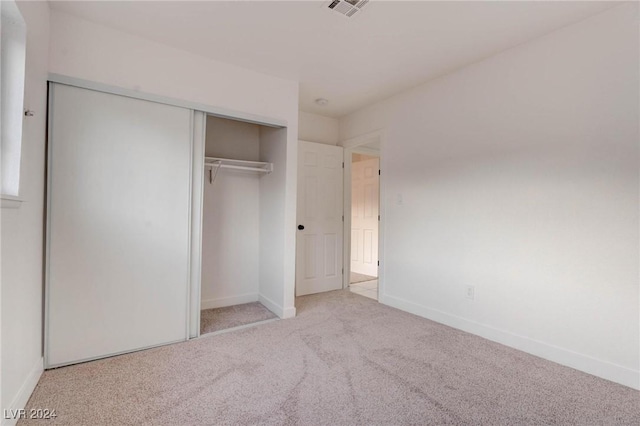 unfurnished bedroom featuring light carpet and a closet