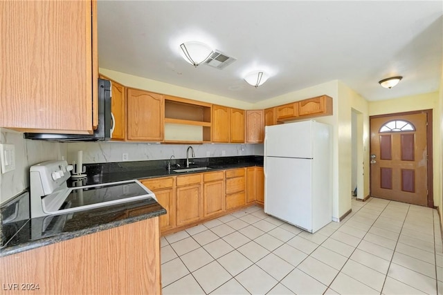 kitchen featuring sink, white fridge, dark stone counters, light tile patterned floors, and range