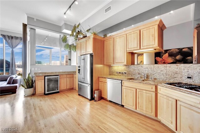 kitchen with decorative backsplash, beverage cooler, light brown cabinetry, and appliances with stainless steel finishes