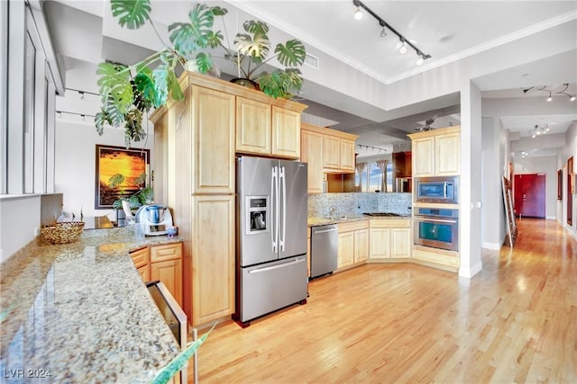 kitchen with crown molding, light hardwood / wood-style flooring, light stone countertops, and appliances with stainless steel finishes