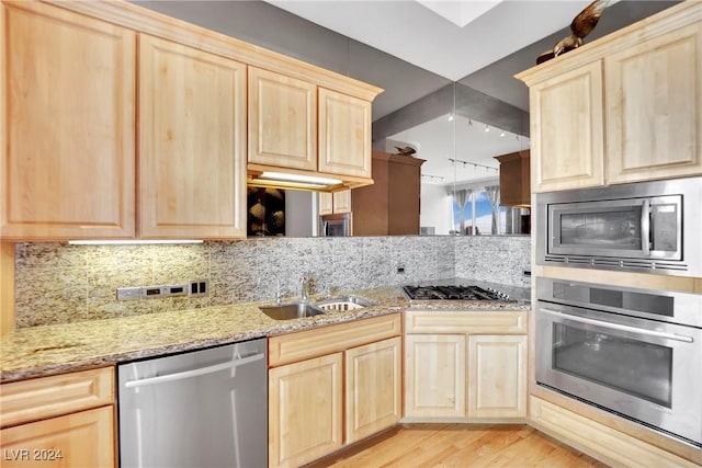 kitchen featuring light stone countertops, tasteful backsplash, stainless steel appliances, sink, and light hardwood / wood-style floors