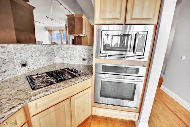 kitchen with decorative backsplash, light hardwood / wood-style floors, track lighting, and appliances with stainless steel finishes