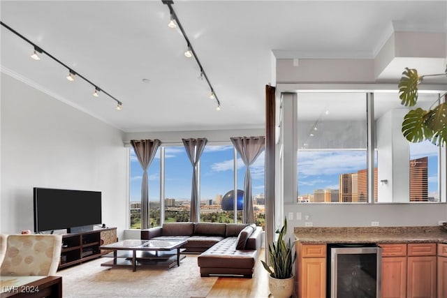 living room with bar area, rail lighting, crown molding, wine cooler, and light hardwood / wood-style flooring