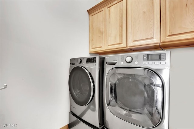 laundry area with washing machine and dryer and cabinets