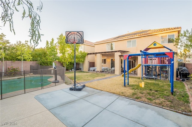 view of basketball court featuring a fenced in pool, a playground, and a yard