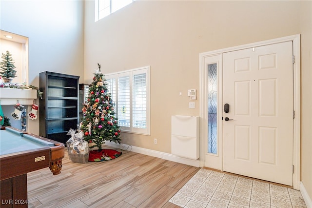 foyer entrance with a towering ceiling, light hardwood / wood-style floors, and pool table