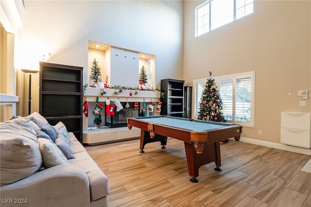 playroom with plenty of natural light, a towering ceiling, pool table, and light hardwood / wood-style flooring