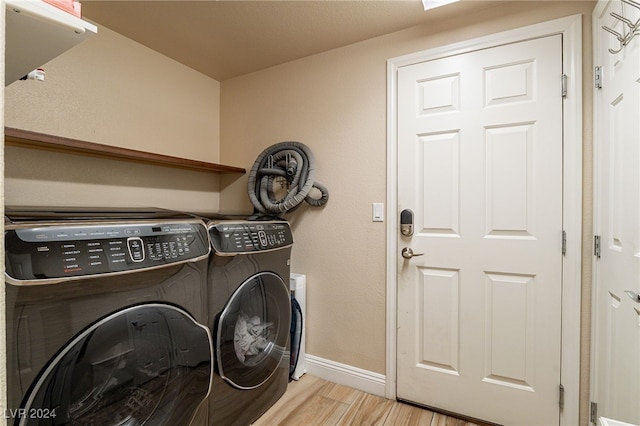 laundry room featuring separate washer and dryer and light hardwood / wood-style flooring