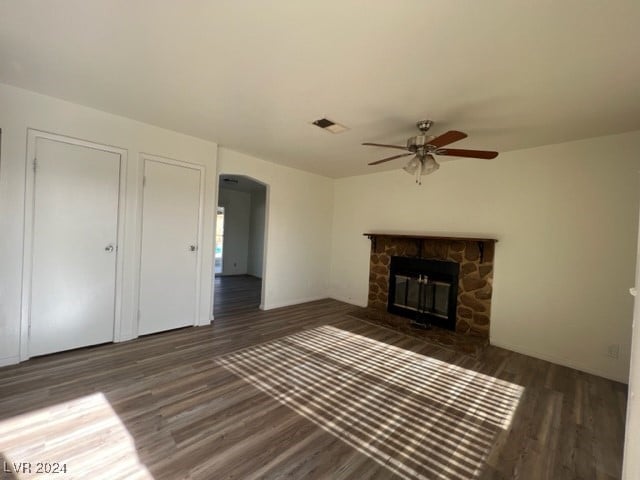 unfurnished living room with a fireplace, ceiling fan, and dark wood-type flooring