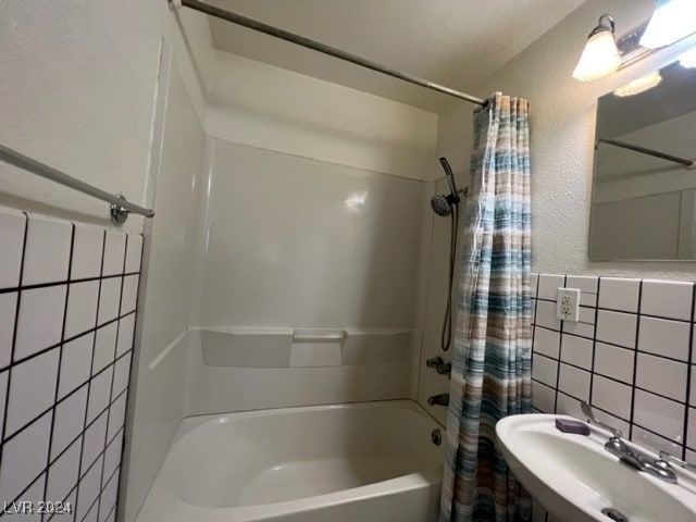 bathroom with shower / bath combo, sink, and tile walls