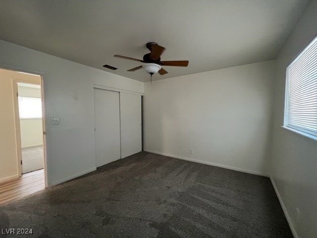 unfurnished bedroom with a closet, dark carpet, and ceiling fan